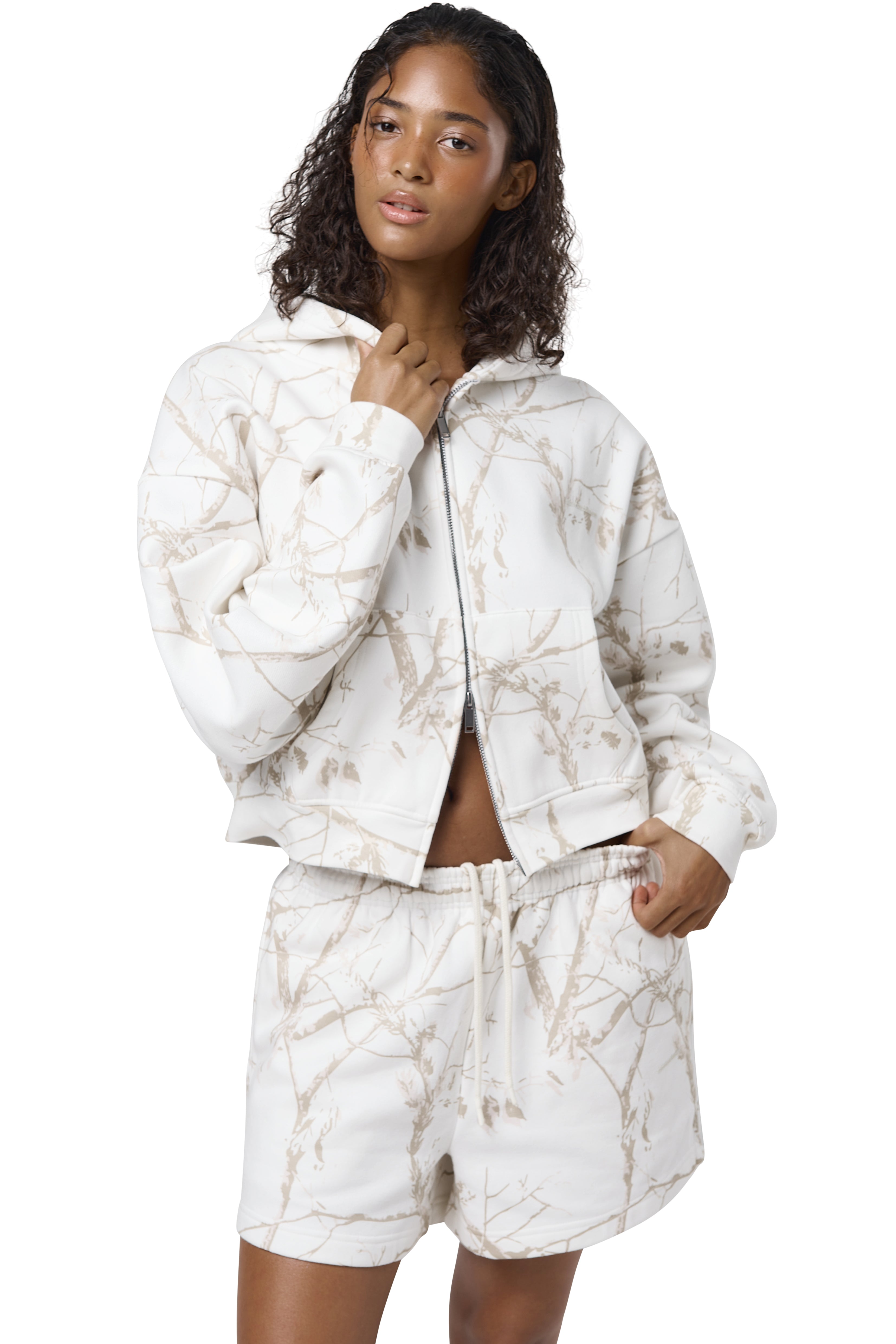 Women's high-waisted white lounge shorts with twig camouflage print, adjustable drawcord waist, and Sisters and Seekers logo to the hip